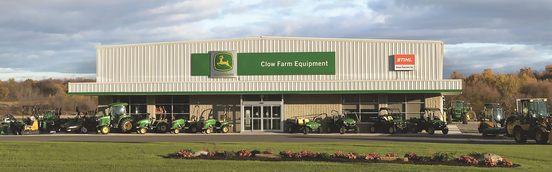 Farm equipment dealership with green-and-tan vertical rib facade and a glass showroom front